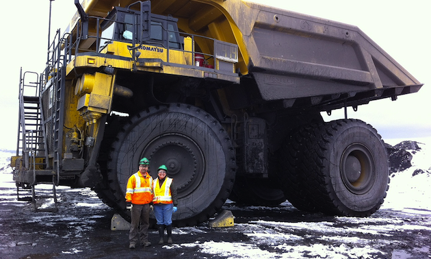 Roland and Elsie Antuna stand in front of a haul truck at Peace River Coal