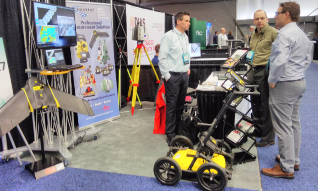 Peter Willis and Parker Adams speak with a delegate at the Spatial Technologies booth.