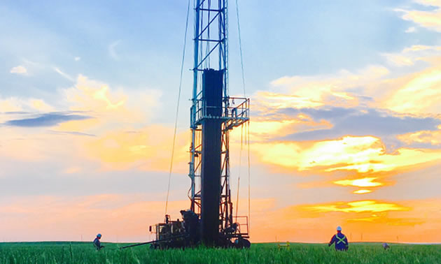 Oil well silhouetted against colourful sunset.