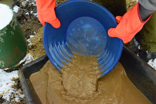 Lathem pours out the last of the sandy water and small rock from the pan.